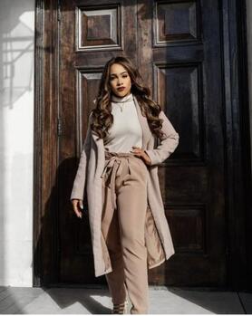 A young woman dressed in beige posing in front of a door
