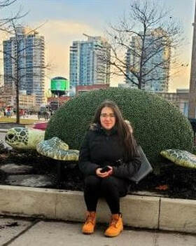 A young woman sits by a topiary of a turtle